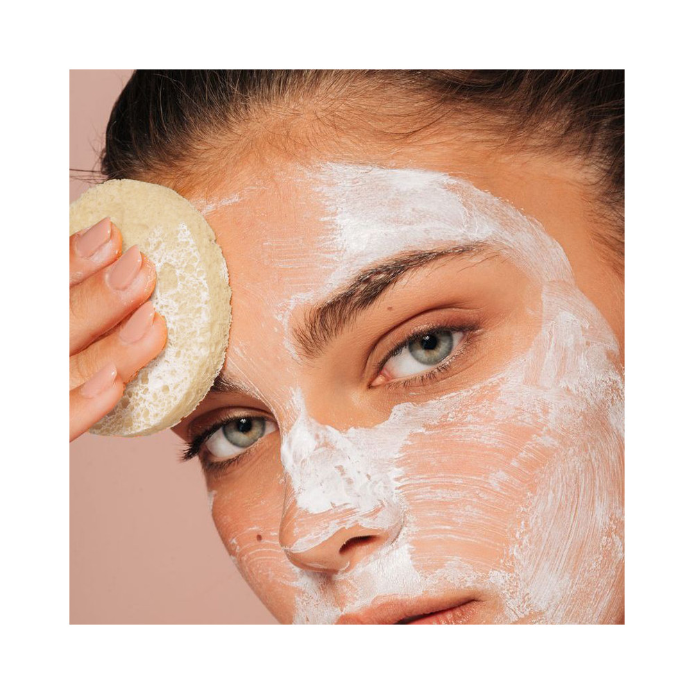woman using a sponge to remove her makeup